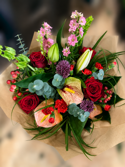 Ruby Charm - A striking bouquet combining rich reds, soft pinks and fresh greenery with delicate seasonal accents.